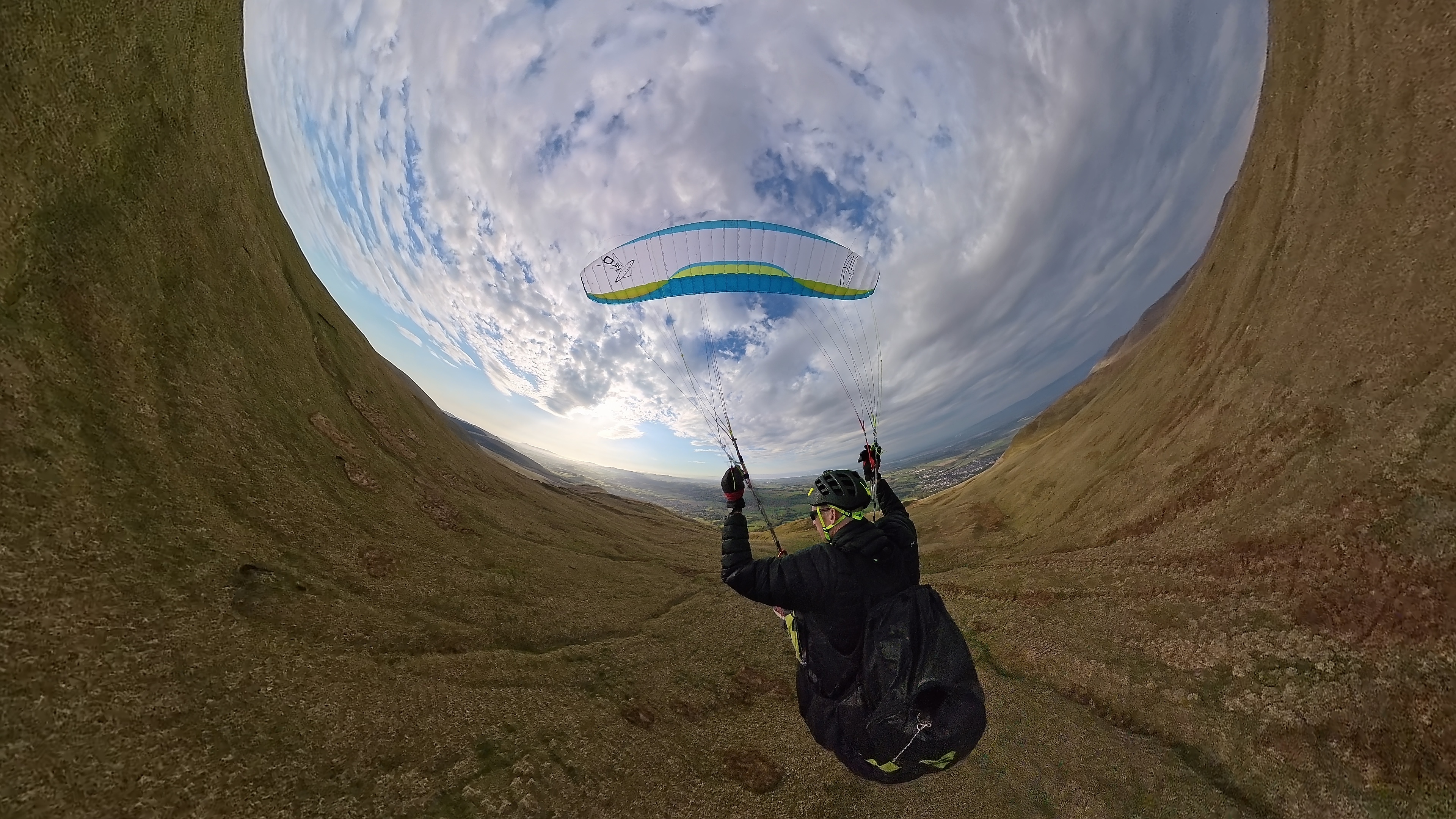Paraglider wing and landscape from the air.