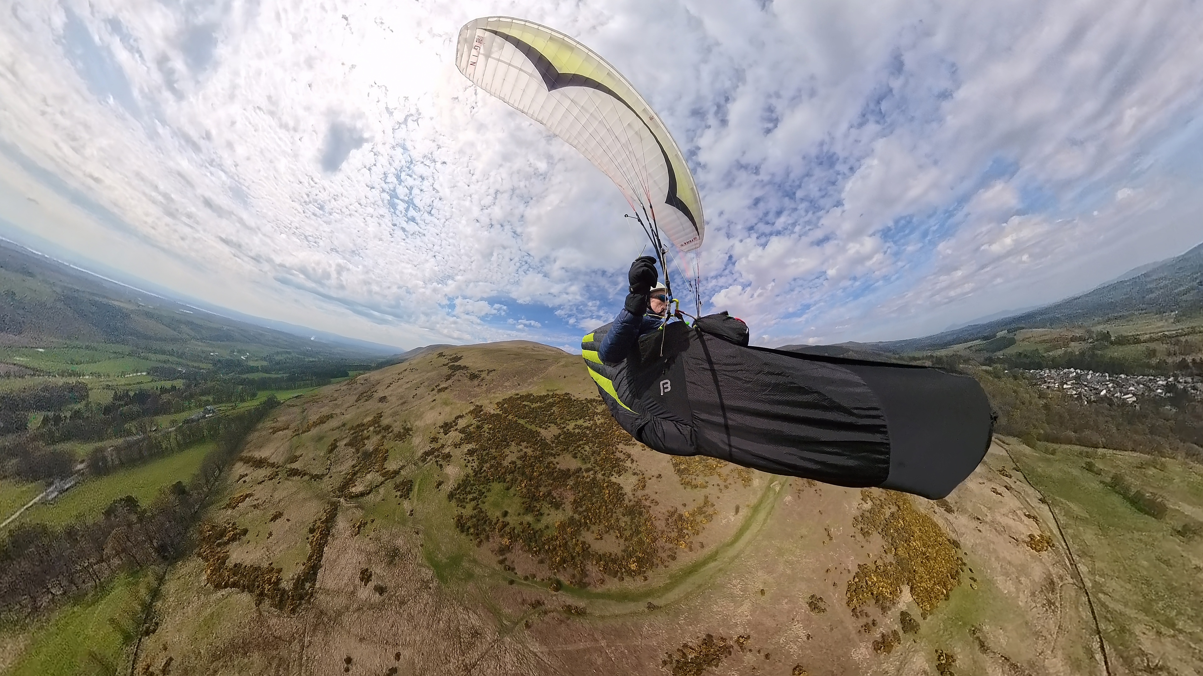 Paraglider flying across open country.